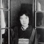 Photo of writer Yosano Akiko standing by a window.