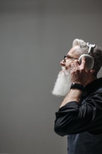 Older man in profile listening to music on headphones.