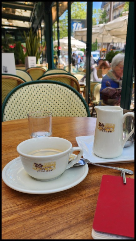 A cafe table in Paris with a cup of coffee and a notebook